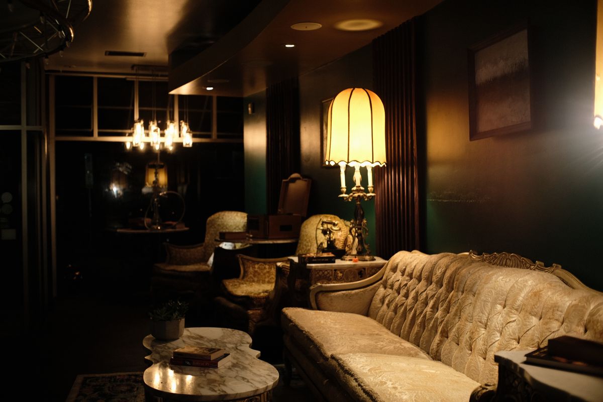 HOKAH lounge interior — tufted sofa, vintage lamp, dark moody atmosphere